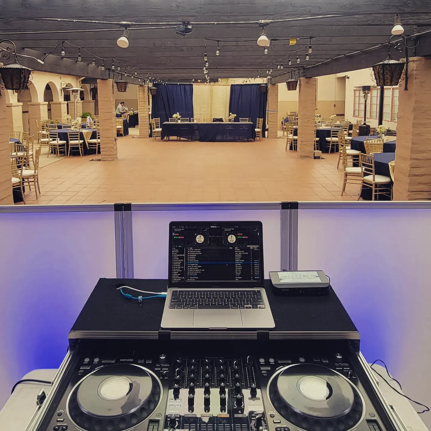 Banquet hall set for dinner above a lit DJ controller