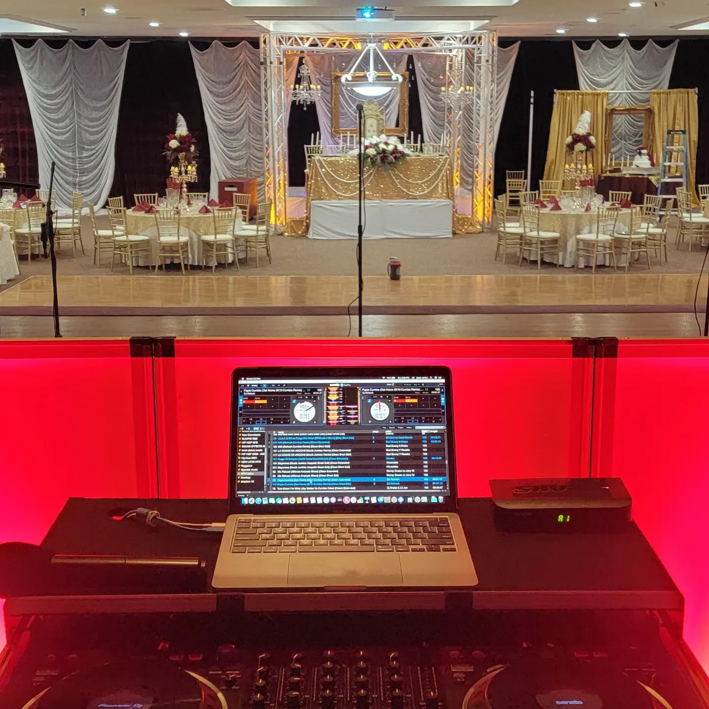 Draped ballroom washed in red uplighting behind the decks