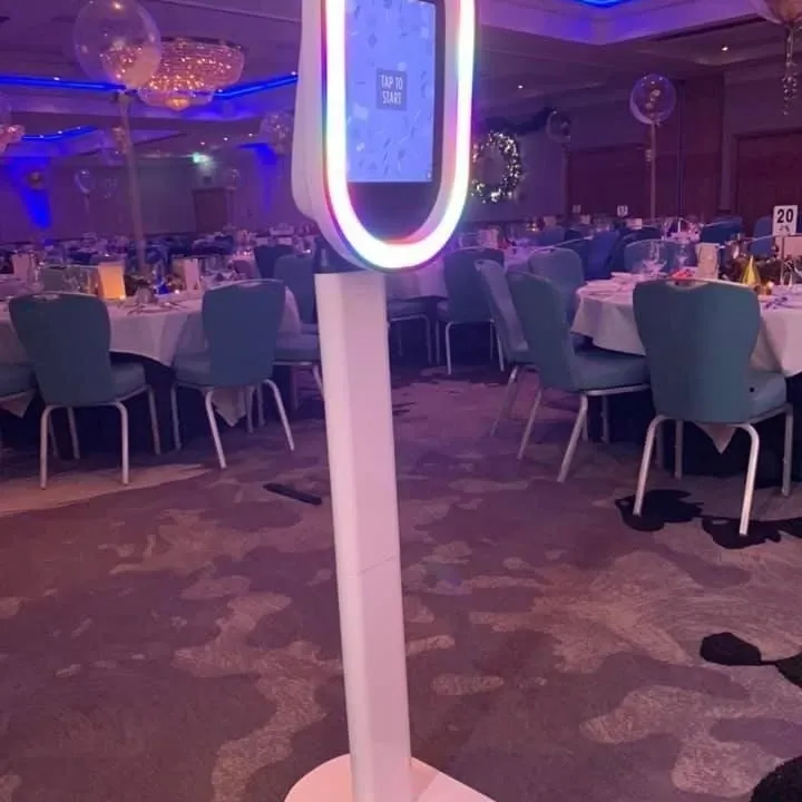 Ring-lit photo booth standing beside the reception tables