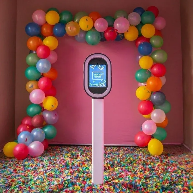 Photo booth framed by a full balloon arch on a pink wall