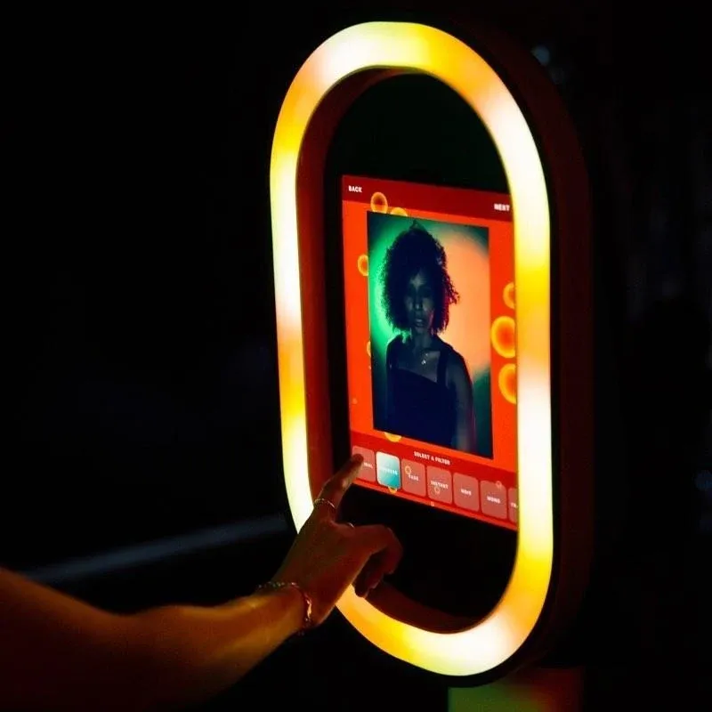 Hand touching the glowing screen of the ring-lit photo booth