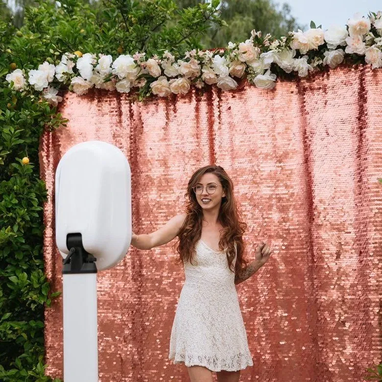 Guest at the photo booth in front of a rose sequin backdrop