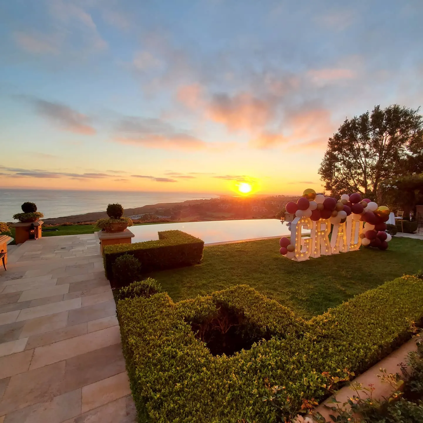 Balloon arch on a clifftop lawn at sunset