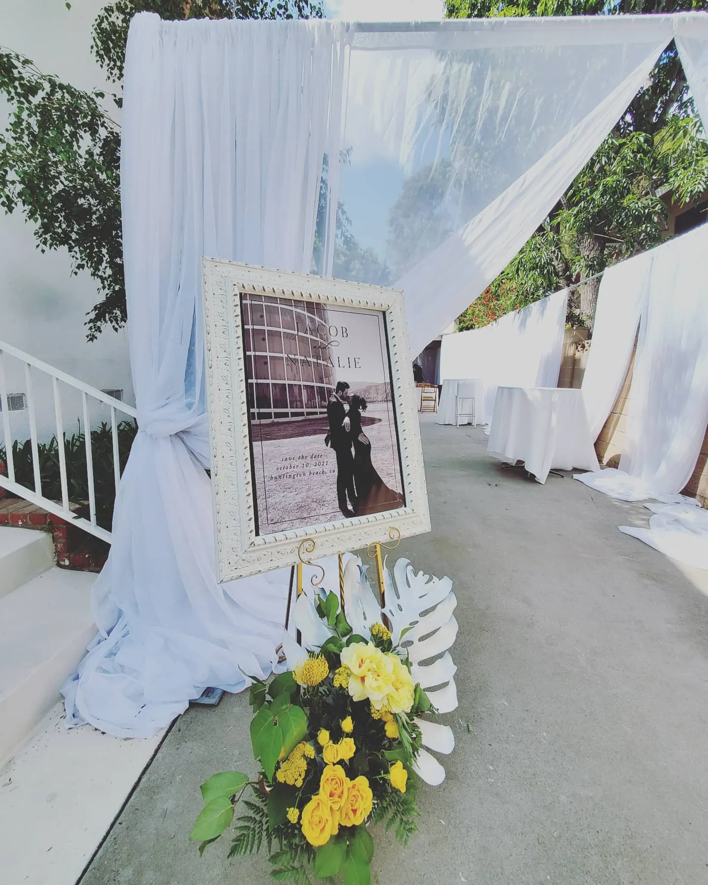 Draped wedding entrance with a framed portrait and flowers