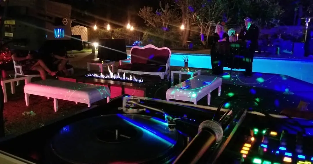Outdoor lounge furniture glowing at night beside the DJ booth