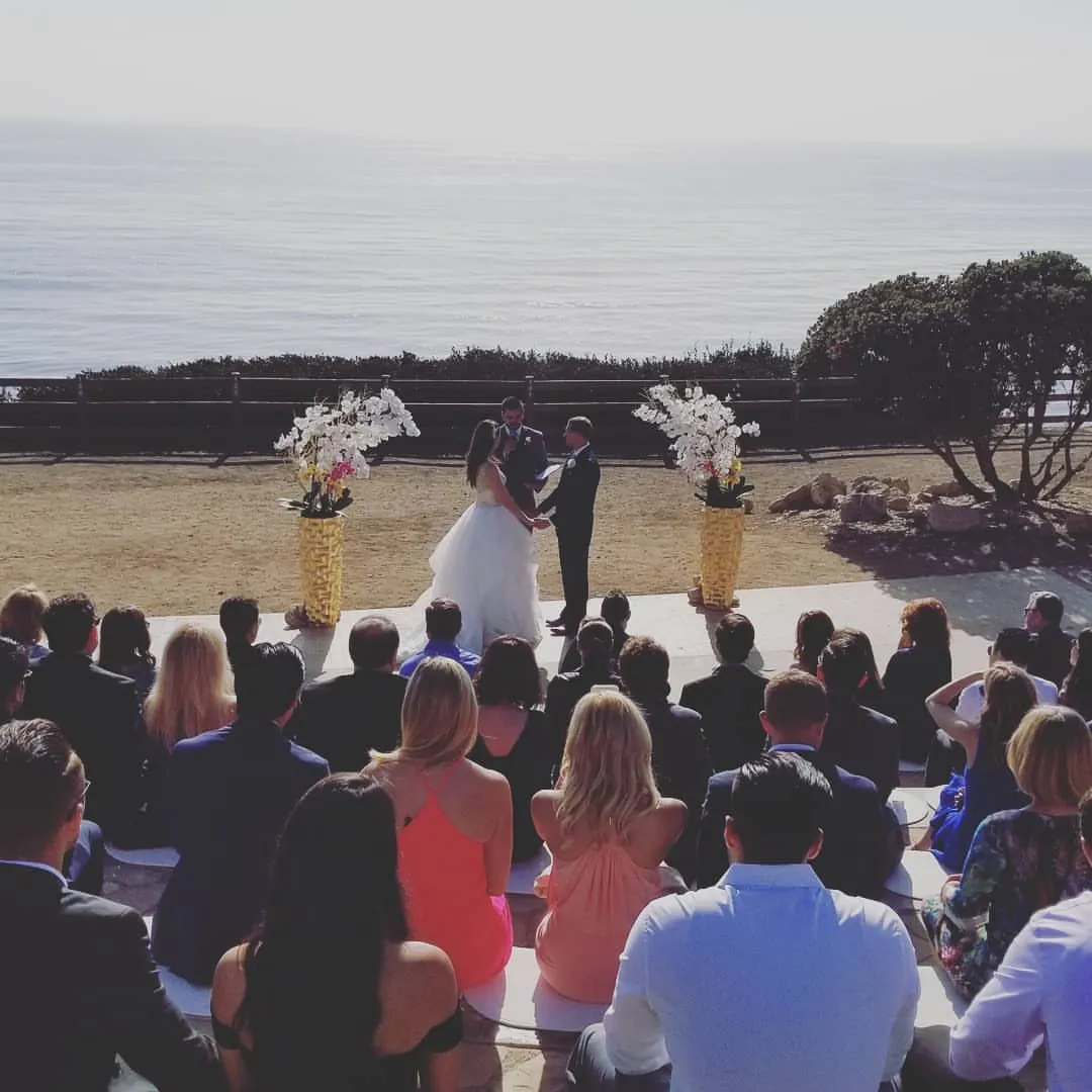 Outdoor wedding ceremony with seated guests facing the couple