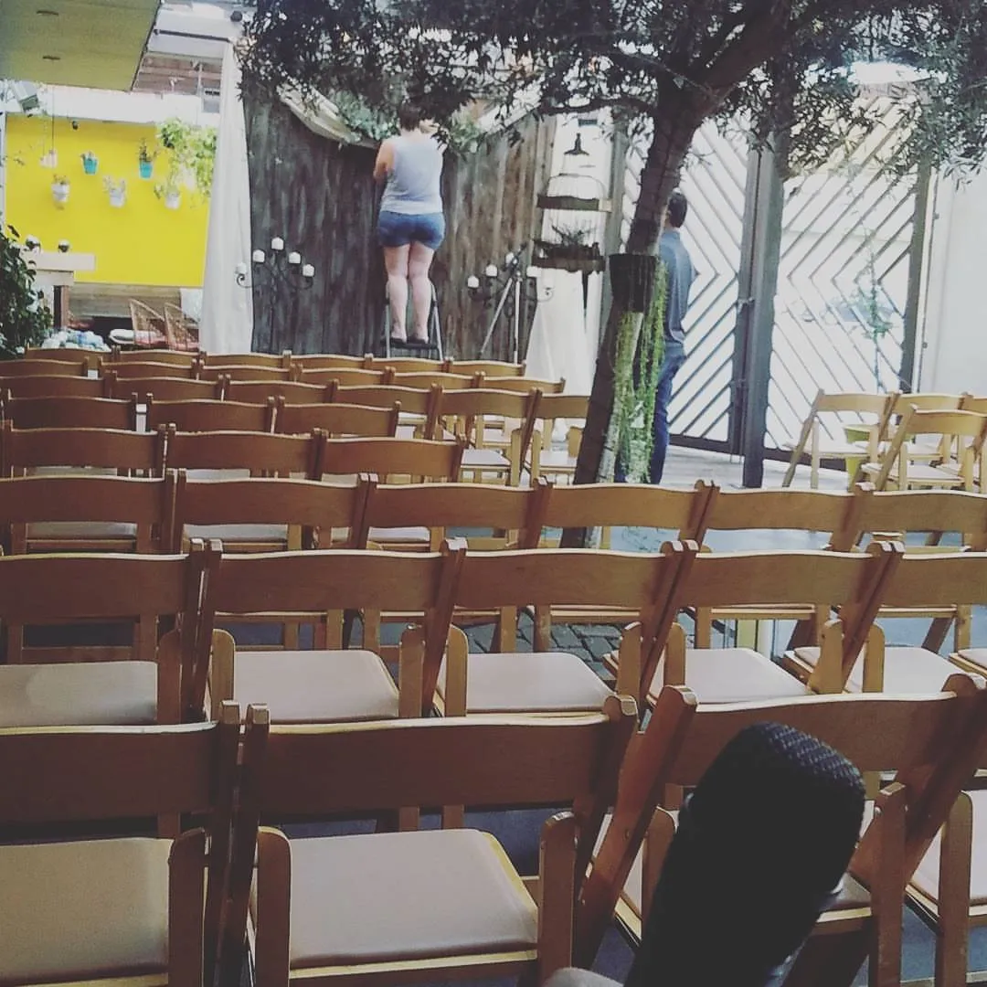 Rows of ceremony chairs being set up in a garden