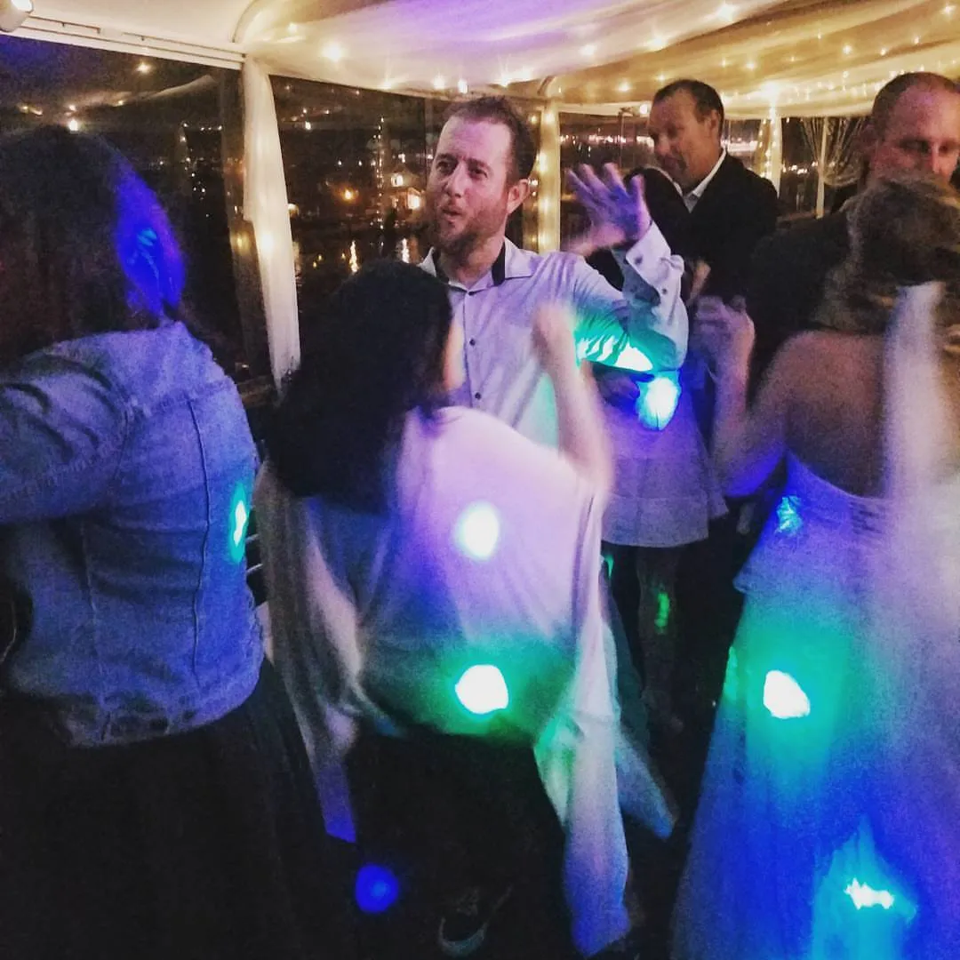 Guests dancing under LED glow sticks on a dark floor