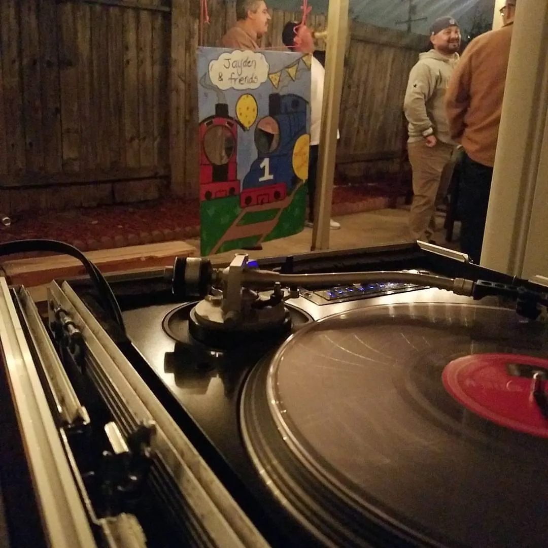 Record spinning at a backyard event with guests behind